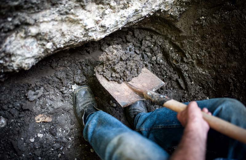 Man digging a hole in the ground with shovel and spade